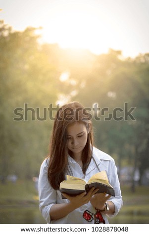 Beautiful asian woman reading a book at garden with happiness and relaxing in the evening with sunset time.