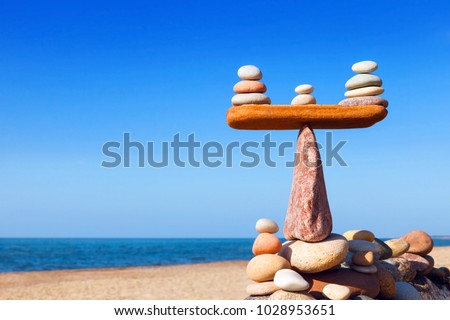 Symbolic scales of stones on a background of blue sky and sea. Concept of harmony and balance. Pros and cons concept. Work life balance