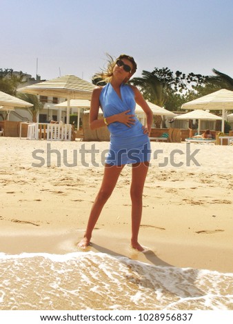 lady in dark glasses is Flirty on the Sunny Sands of the beach, near the water of the red sea, on the background of sun loungers and sun umbrellas