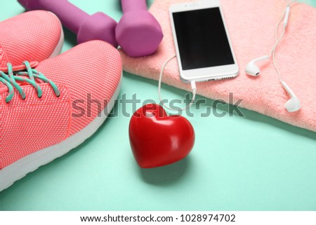 Gym stuff, phone and red heart on color background. Cardio training concept
