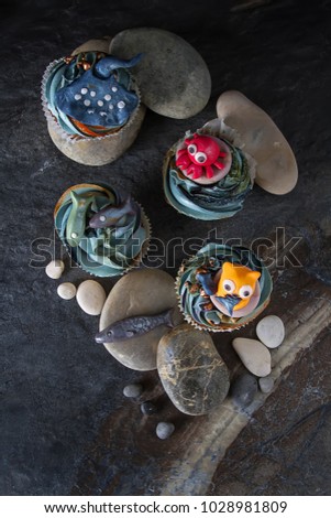 Capcake with animals from mastic and marzipan cat, fish and crab. Decor cake. Dark background