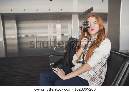 The girl waits for an airport plane with a camera