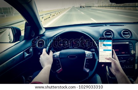 Dangerous driving while writing SMS text message Royalty-Free Stock Photo #1029033310