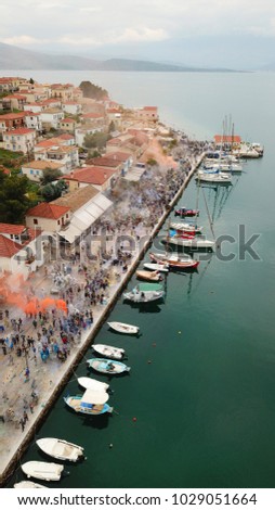 Aerial drone bird's eye view photo of people participating in traditional colourful flour war or Alevromoutzouromata part of Carnival festivities in historic port of Galaxidi, Fokida, Greece