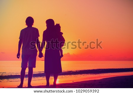 happy romantic couple with small child on tropical beach