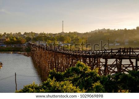 Large bridge made of wood to use crossed from one side to another side of the river, and the sun is falling