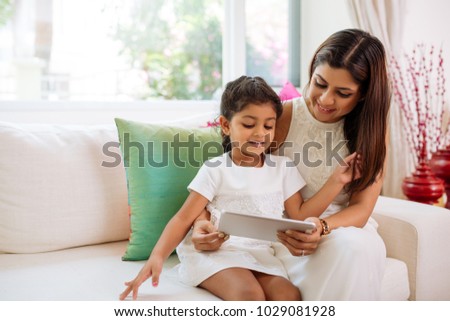 Indian mother and daughter watching cartoons on tablet computer