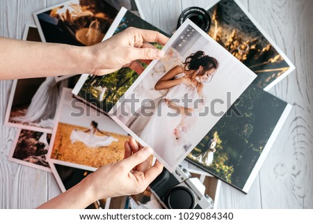 Printed wedding photos with the bride and groom, a vintage black camera and woman hands with photo