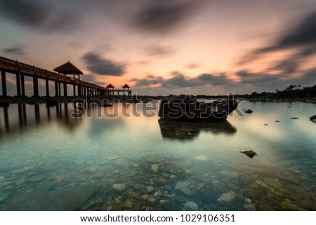 A Long exposure picture of golden sunrise with stone jetty with reflection