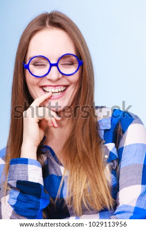Studying, education and fun concept. Happy smiling nerdy woman in weird big glasses. Studio shot on blue background