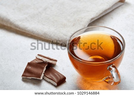 Top view closeup picture of tea in transparent cup with chocolate and cotton napkin on white background, selective focus