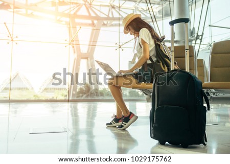 Asian teenage girl is using a laptop to check email or social network or internet at the international airport to travel on weekends. Royalty-Free Stock Photo #1029175762