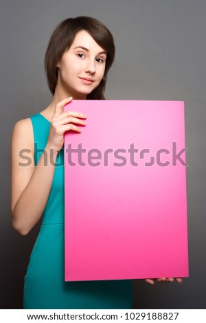 Pink poster. Young beautiful woman  holding  sheet  paper. Place of copy for advertising.