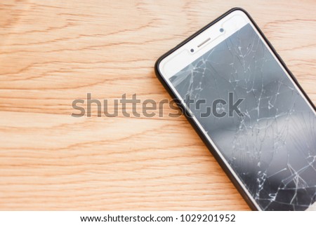 Smartphone with broken screen on the wooden table 