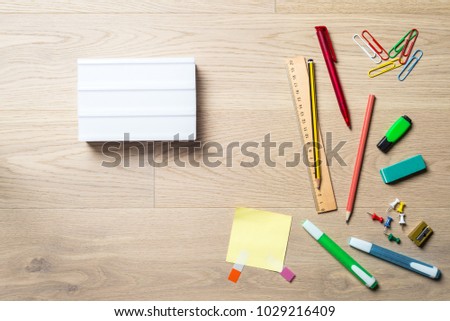 Blank lightbox with copy space for writing a message lying on office desk with pen, pencil, highlighter and ruler as flat lay from bird's eye view