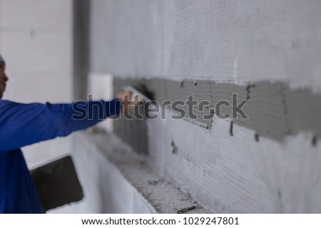 Adhesive plaster for ceramic wall tile work by worker background,construction work.