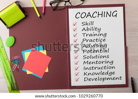 COACHING written in paper sheet on presentation folder and various stationery on wooden table.Business concept.Top view. Royalty-Free Stock Photo #1029260770