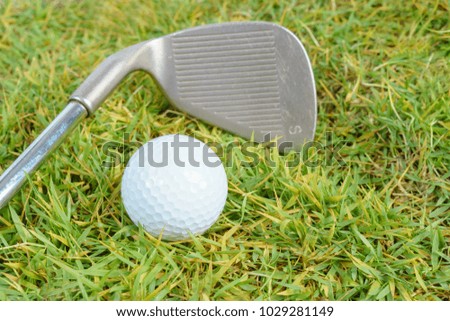 Golf clubs and golf ball on green grass background