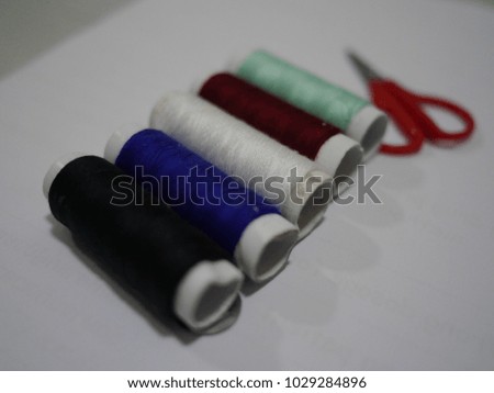 Colorful thread, needle and scissor on the table