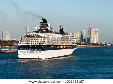 The view of a cruise liner leaving Miami city at dusk with Miami Beach skyline in a background (Florida).