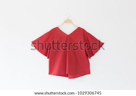 Red colour blouse is clothes hanger on white background. Royalty-Free Stock Photo #1029306745