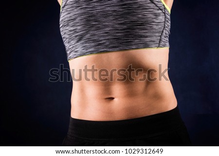 Woman`s flat stomach with press. ABS. Isolated on dark blue background. Workout concept.
