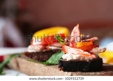 Bruschetta of black bread with beans, cheese, grilled vegetables, peppers and tomatoes and meat