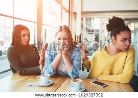 Terrible situation where one girl is sneezing between two of her friends but her friends don't like it. They are trying to stay away from her because it's disgusting. Royalty-Free Stock Photo #1029327352