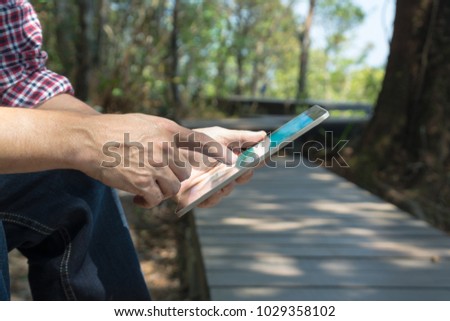 Male Hand use Digital Wireless Tablet PC to read e-mail or E-book and Travel information map while travel Trekking in forest National Park as Internet Technology for Trekker Hiker Telecommunication Co