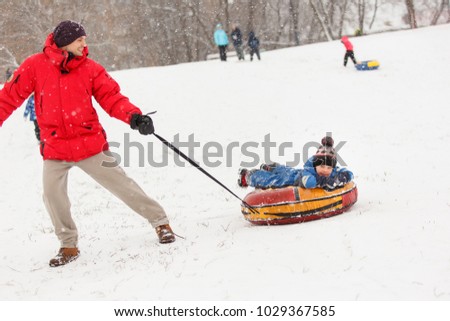 Image of man rolling his son on winter day