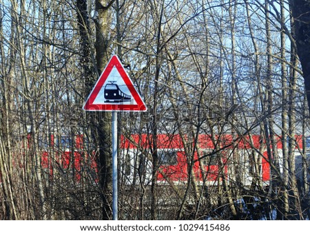 railroad level crossing sign on rural road and train traveling across