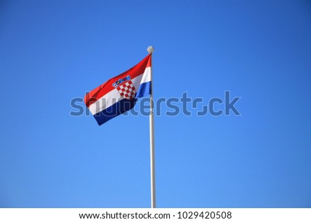 Flag of Croatia with flag pole waving in the wind with blue sky in background