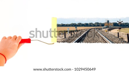 person painting a railroad track on a white wall with a roller brush