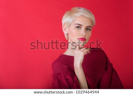 portrait of a beautiful young girl with a short hairstyle on a red background
