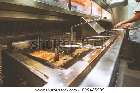 Chips cooking in Fish and Chip shop Royalty-Free Stock Photo #1029465505