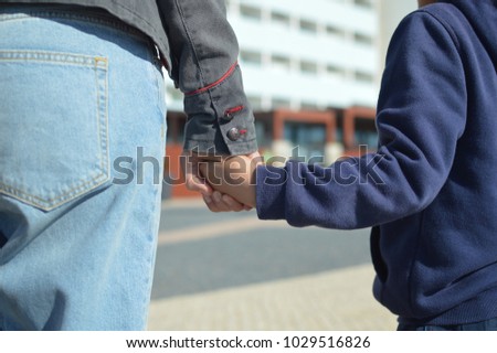 The child holds mum. Closeup on hands over sunny day outdoors background. Caring happiness