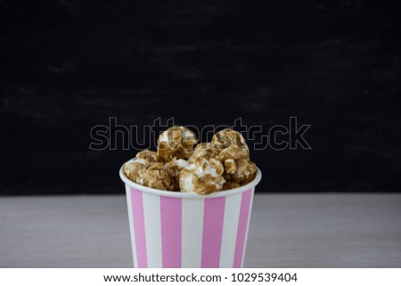 Sweet popcorn on the table. Popcorn in the pink bucket. Snack for the movies. Cinema set. Unhealthy food.