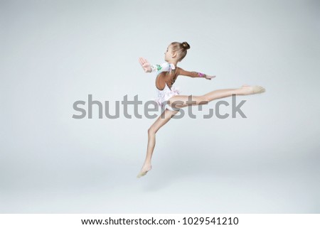 Rhythmic gymnastics caucasian blonde girl in dress for shows with flowers shows acrobat balance on white background isolated