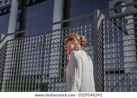 Beautiful business woman walks down the street while talking on her mobile phone