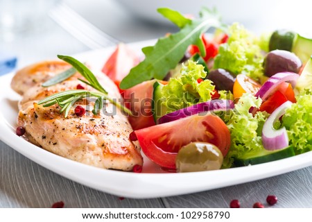 Grilled chicken breast with tomatoes, red pepper, organic green and kalamata olives, red onion, lettuce and fresh rocket and rosemary. Home made food. Concept for a tasty and healthy meal. Close up. Royalty-Free Stock Photo #102958790