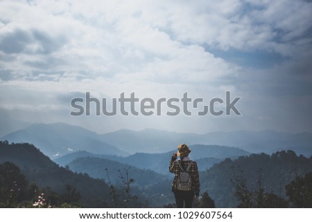 Young woman enjoying at a hill with blue sky. Sunrise in the morning. People have a trekking trips to a fog valley. Picture in vintage tone. 