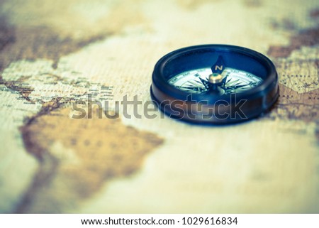 An old compass on vintage world map. Compass on map background. Close-up of ancient boat compass aboard on old world map. Focus on Caribbean Sea, treasure hunt.