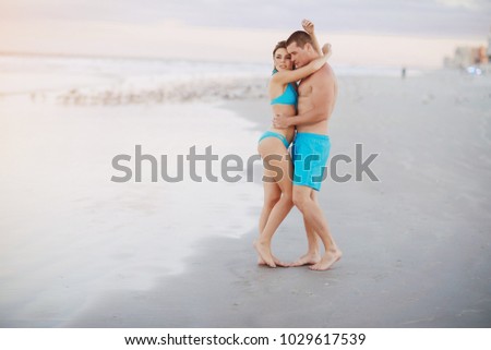 young sporty couple walking on the beach and posing for the photographer