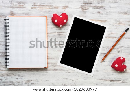 Blank photo frame and notepad on wooden table