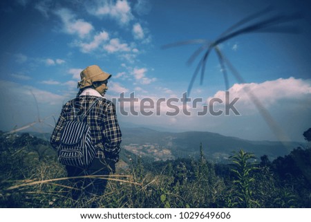 Young woman enjoying at a hill with blue sky. Sunrise in the morning. People have a trekking trips to a fog valley. Picture in vintage tone. 