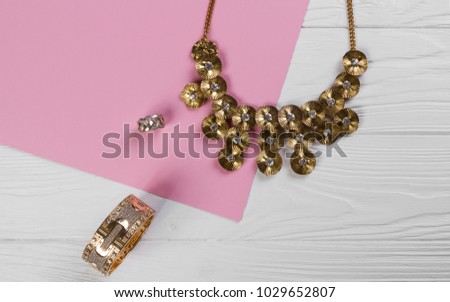 Golden Jewelry set on pink paper and white wooden background