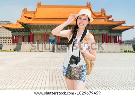 A brilliant picture photo of a positive girl standing in front of Chiang Kai-shek Memorial Hall with her arms raising. 