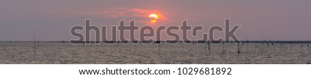 Sun is falling over the sea in panoramic style and has fishing gear of fishermen, The key element in the middle of the image is the layout of the letter and background.
