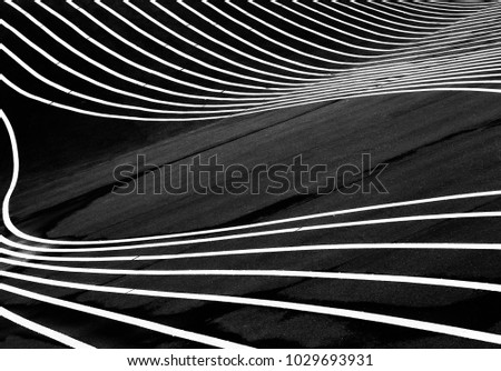 White lines flow on black asphalt. The white lines against the black asphalt create a very abstract image. 