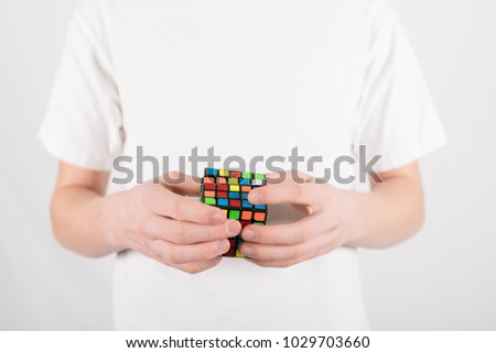 Teenage boy speed solving 5x5 cube puzzle in white T-shirt against white background